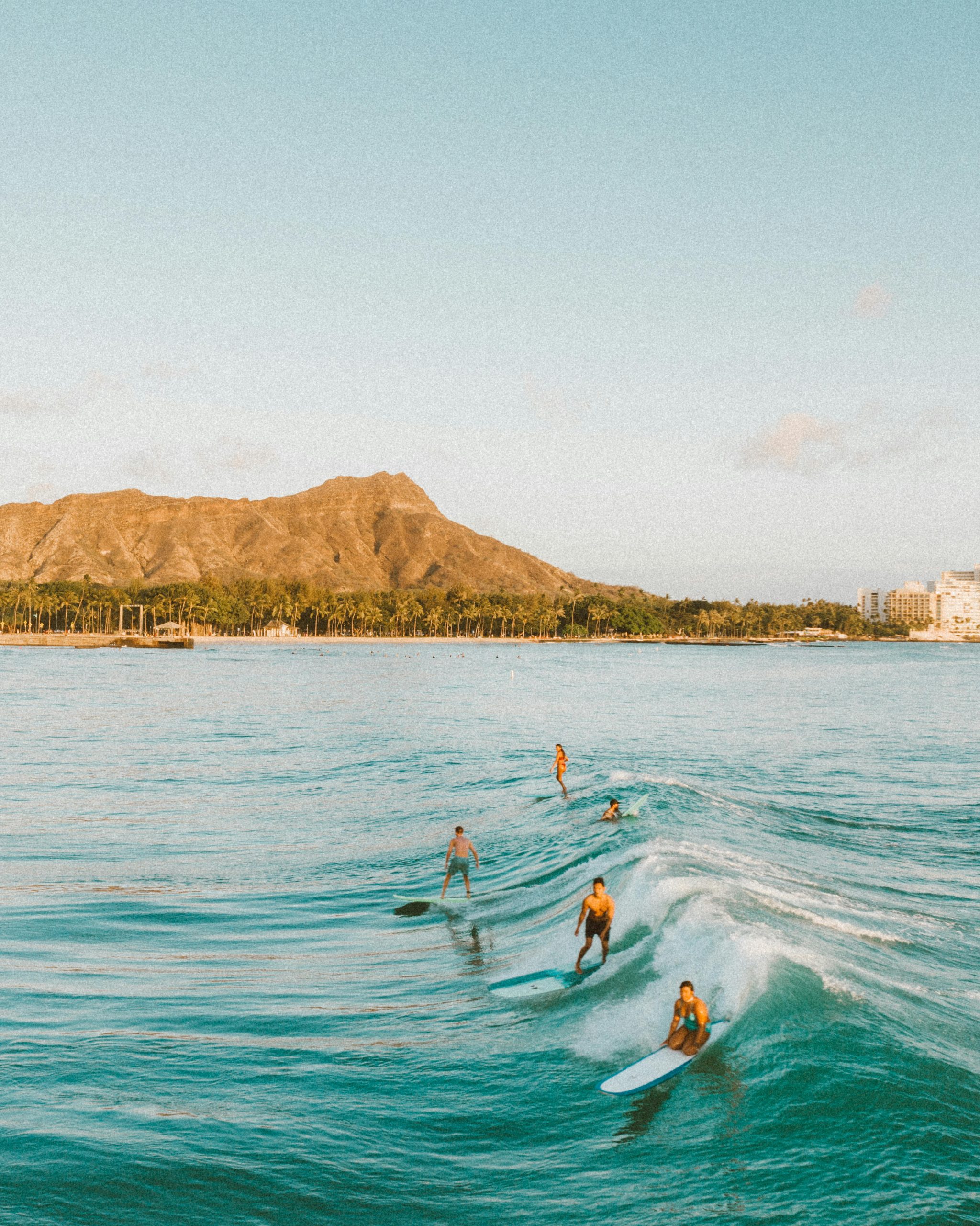 Surfers catching waves near the famous Diamond Head in Hawaii.